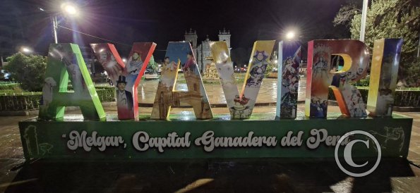 City name sign in the Plaza de Armas at night